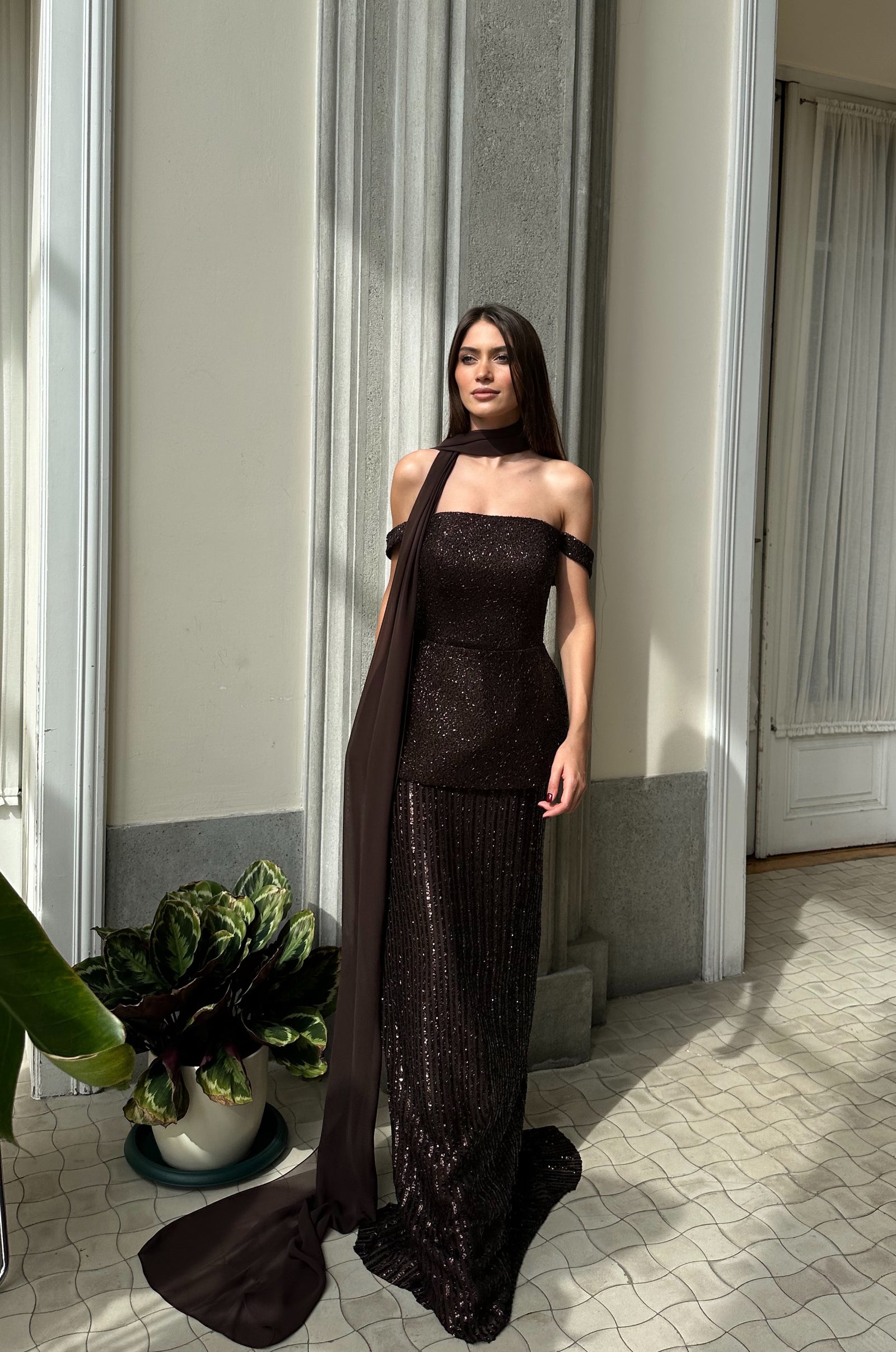 Model wearing Marvin off-shoulder sequin evening gown in deep chocolate with elegant silhouette