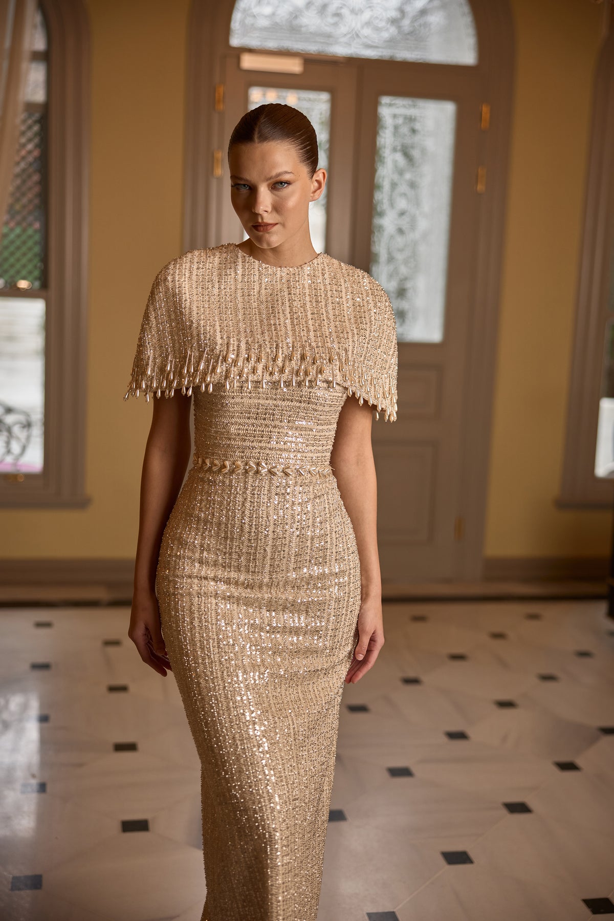 Model wearing Erin gold sequin couture gown with glamorous fitted silhouette
